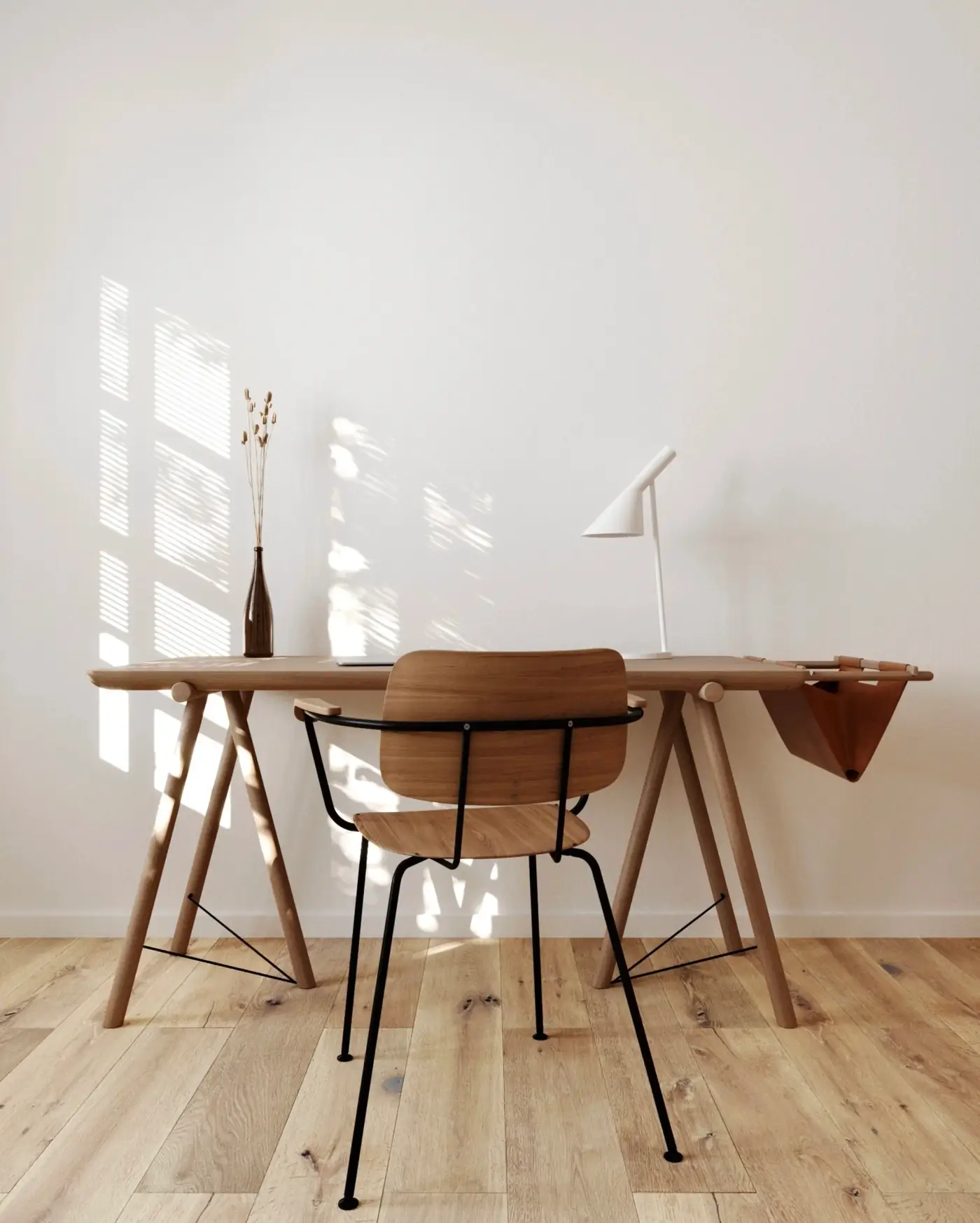 A sunlit wooden desk and chair against a pale wall